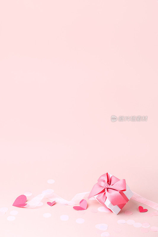 时尚的礼盒与大粉红色蝴蝶结和温柔的纸工艺粉红色的心在粉红色的背景，拷贝空间，贺卡，横幅，传单，明信片为圣瓦伦丁节，浪漫假期，婚礼，生日