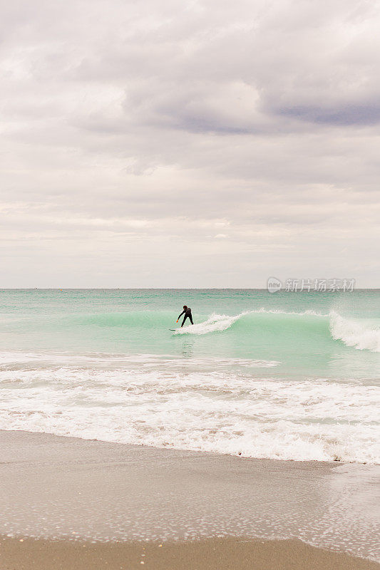 2021年1月的中午，冲浪者在蓝绿色的海浪上冲浪，横扫佛罗里达州的朱诺海滩