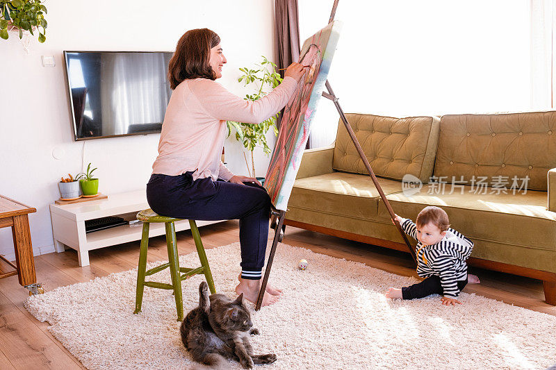 妈妈在画画，她的孩子在地板上玩