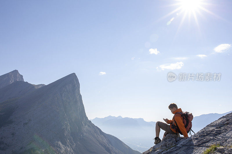 年轻人停在岩石脊顶，在群山之上