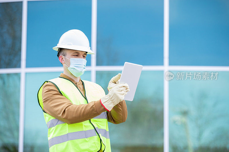 现代商业建筑竣工后，建筑工程师或建筑工人在施工现场使用数字平板电脑