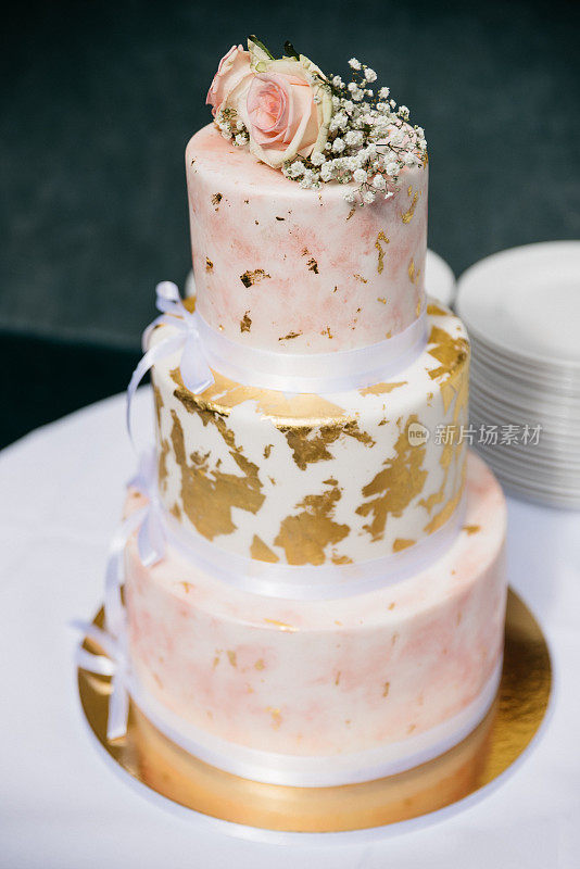 优雅的婚礼蛋糕与金色和玫瑰的细节