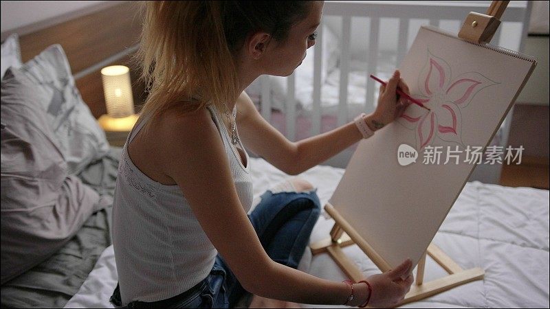 年轻女子在卧室里画画。艺术家在家工作。2019冠状病毒肺炎大流行封锁期间不要外出。
