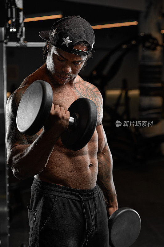 强壮和肌肉发达的黑皮肤的男人在现代化的设备在健身房训练