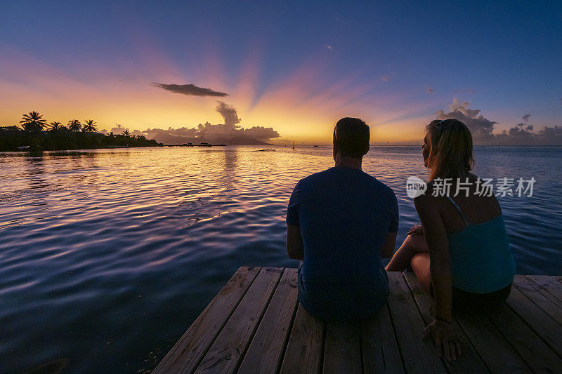日落时分，一男一女坐在码头上。