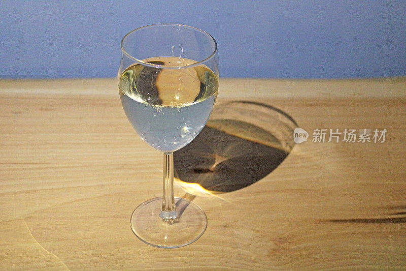 白葡萄酒装在酒杯里，放在木桌上