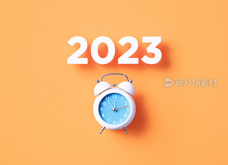 2023坐在橙色背景的白色闹钟上面