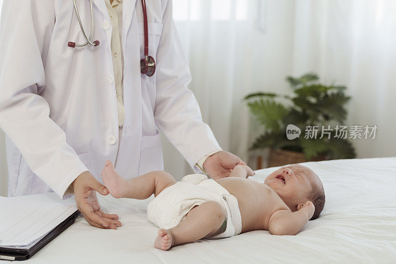 亚洲妇女谁是儿科医生健康检查生病的新生儿躺在白色的床在医院的检查室