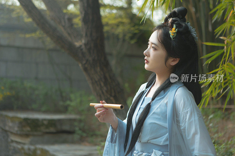 汉服里的中国美女手持长笛在湖边