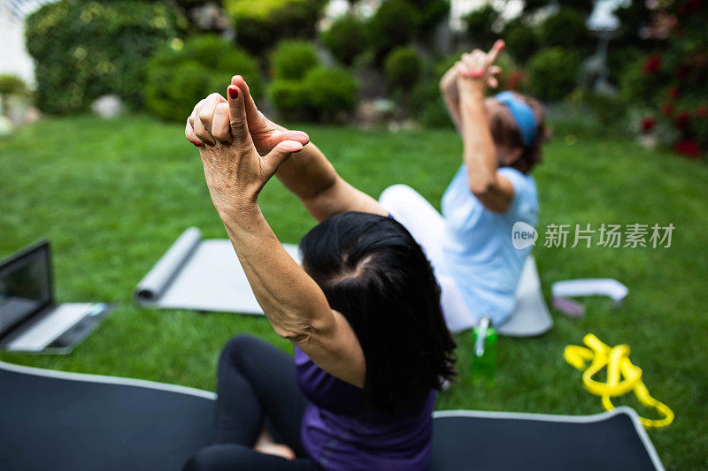 在在线瑜伽课上，一个成熟女性的手与所有手指交叉，除了食指和拇指，而侧伸的特写