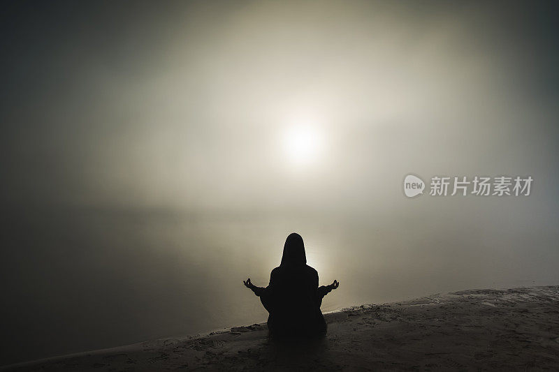 男人的剪影在雾蒙蒙的黎明背景下沉思。