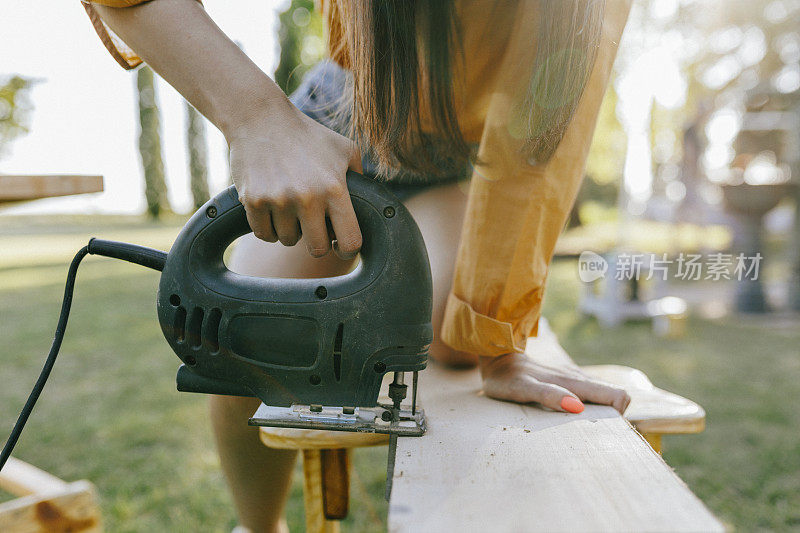 女木匠用电锯锯木头的特写。用电动拼图做木工活的女人