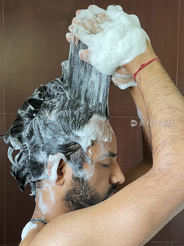 印度男子淋浴洗头的特写图片，使洗发水泡沫卷发，侧视图