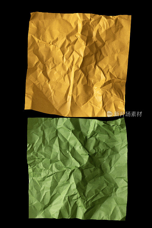 黑色底色的绿色和橙色皱褶纸。纹理、背景