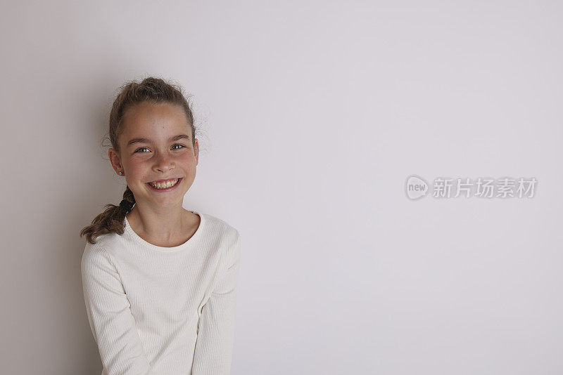 一个穿着白衬衫的情绪化少女，十一二岁在孤立的白色背景上。儿童工作室肖像。放置文字，以复制空间为铭文，广告儿童用品。