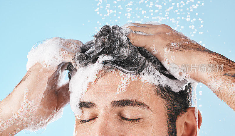 脸，水溅和洗发淋浴的人在工作室孤立的蓝色背景。水滴，头发护理和男模洗涤，洗澡或清洁健康的皮肤，健康或皮肤护理卫生