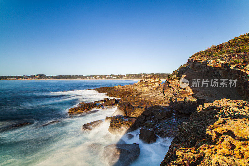 清晨的阳光照耀着海岸，海浪冲刷着岩石