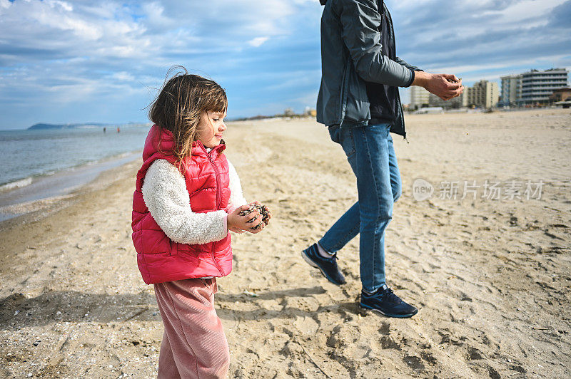 孩子和爸爸一起玩，手里拿着海石和贝壳。