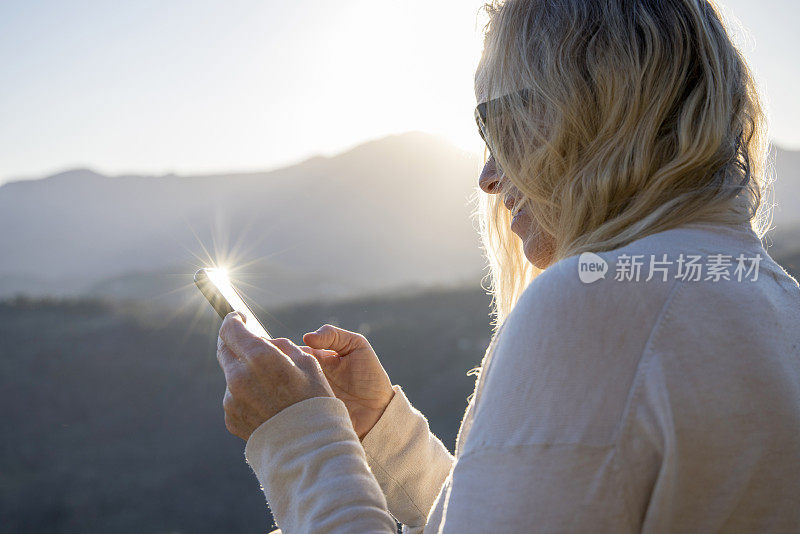 成熟的女徒步旅行者在远山的山顶上放松