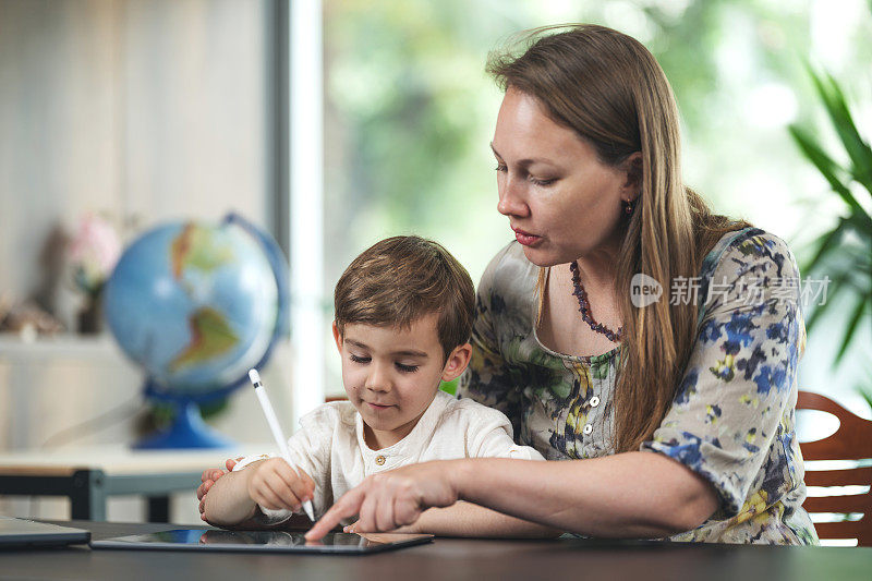 母亲和儿子在数码平板电脑上画画