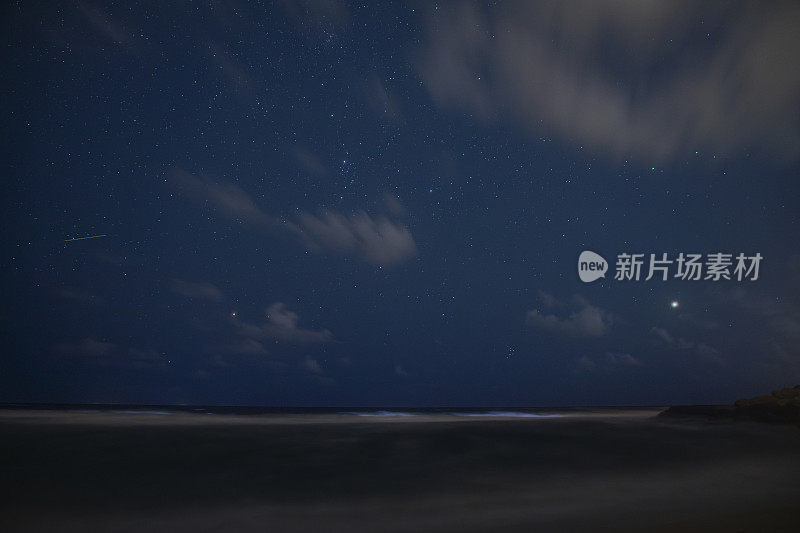 繁星点点的天空和夜晚海滩上的木星