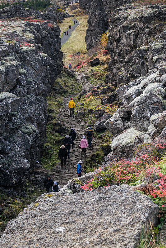 人们在冰岛Thinvellir国家公园的构造板块之间行走