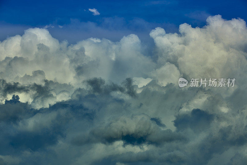 蓝蓝的天空中，云引人注目。多层云从远处看是由黑云和白云组成的。