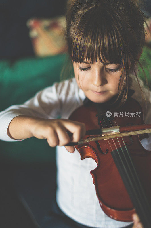 年幼的孩子，刚上小学的女孩在练习拉小提琴