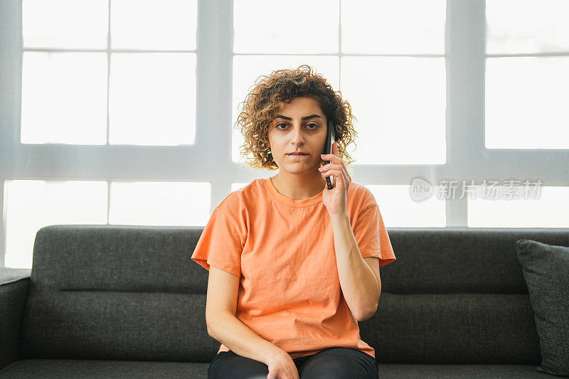 一个体贴的女人坐在客厅的沙发上讲电话