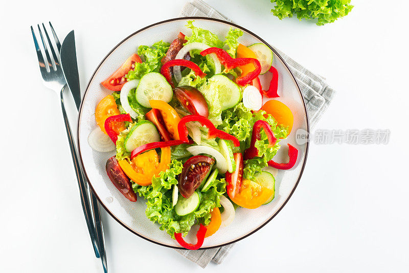 蔬菜沙拉，新鲜的西红柿，黄瓜，洋葱，生菜在白色盘子。