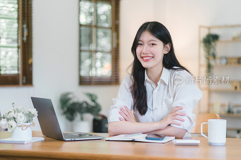 快乐的千禧一代亚洲女商人在家用笔记本电脑工作。