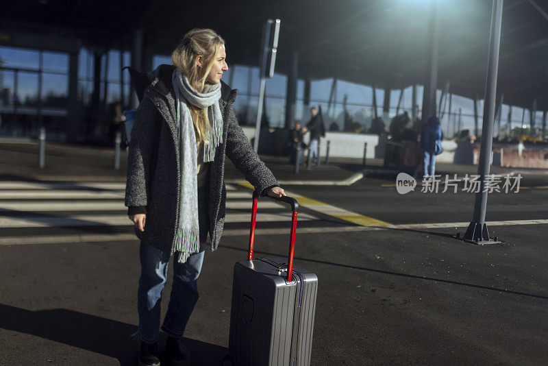 一名女子拖着一只手提箱离开机场