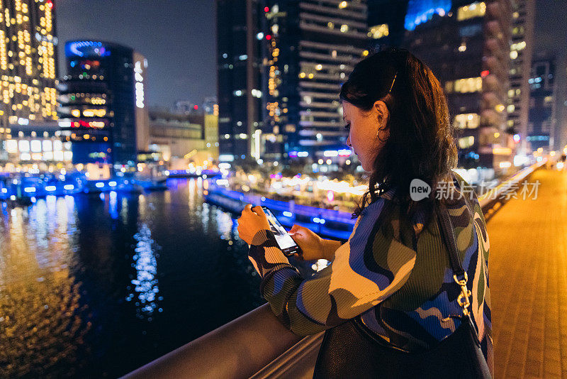 迪拜码头夜间使用智能手机的女企业家