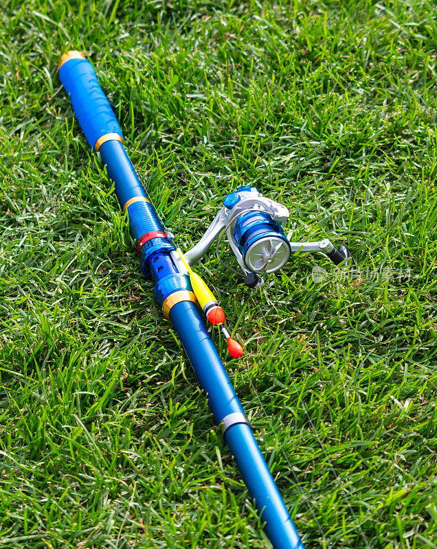 一根蓝色的鱼竿躺在绿色的草地上