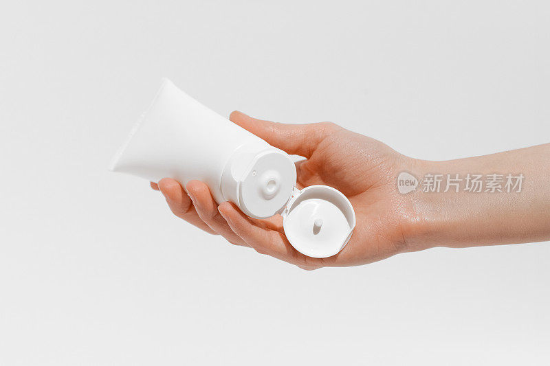 女性手握白色开放乳霜管模型在白色孤立的背景。美容产品的概念，将化妆品涂抹在皮肤上，每日营养补水。