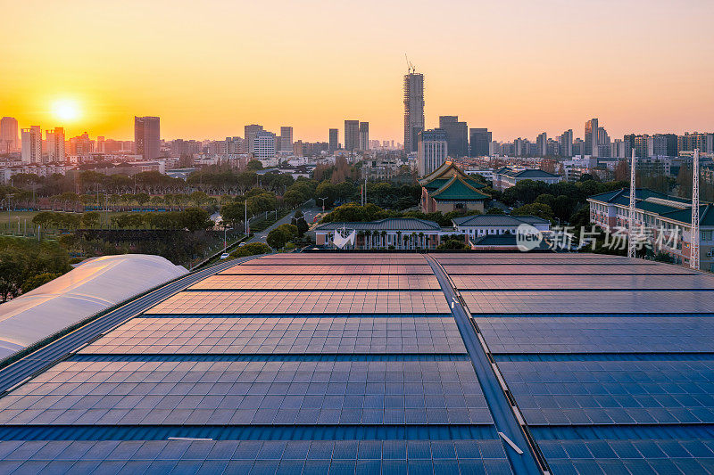 黄昏时分屋顶上的太阳能电池板与城市天际线