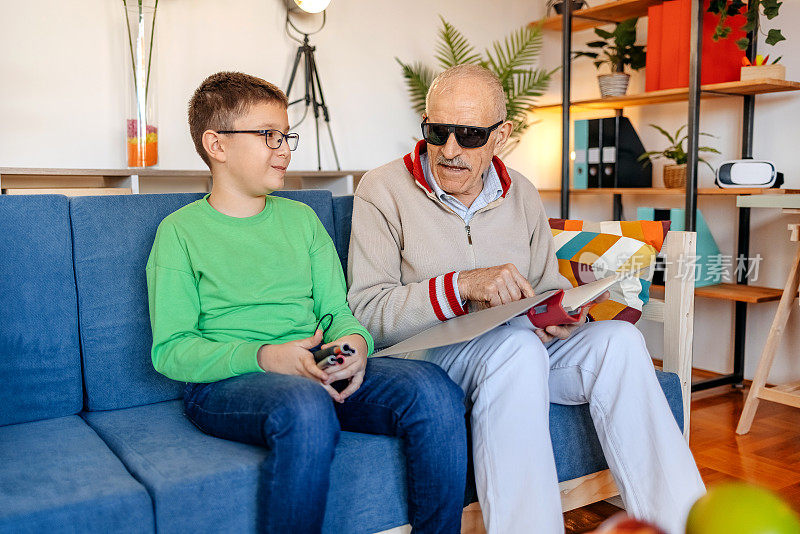 一个盲人老人和孙子坐在客厅的沙发上