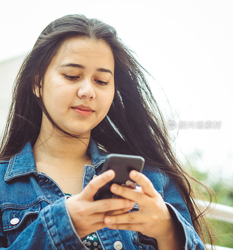 年轻的亚洲女大学生在户外使用手机