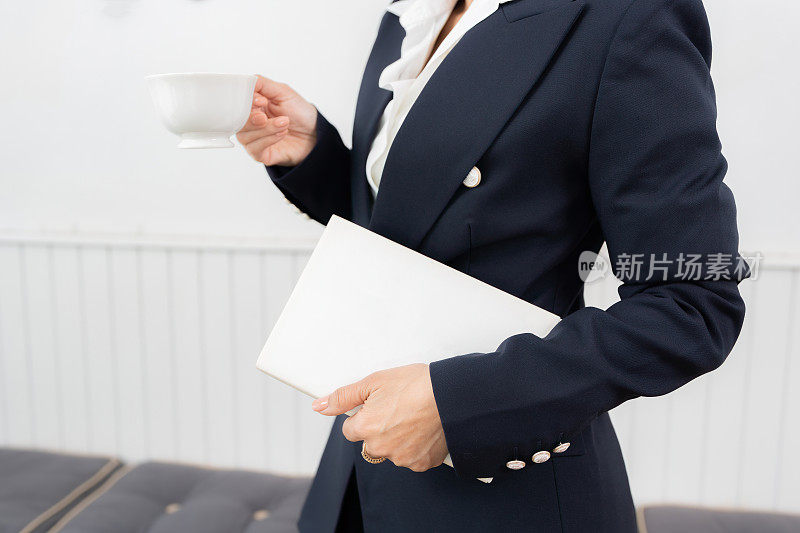 一位亚洲女商人的头像，她正在读一本关于投资和股票的书，在咖啡馆喝咖啡，穿着西装，在咖啡馆的办公空间里。干净，留白