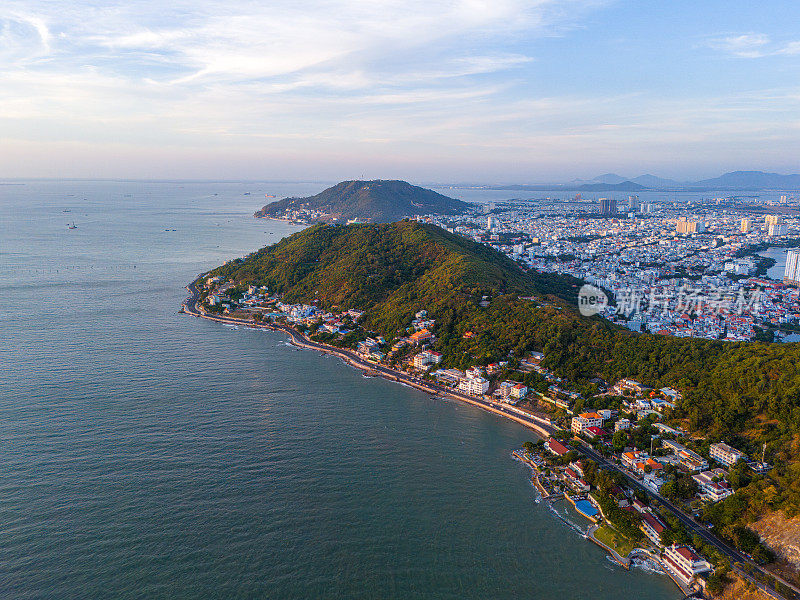 从上面俯瞰云头海岸全景，海浪、海岸线、街道、椰子树、越南Nho山后面的基督国王雕像