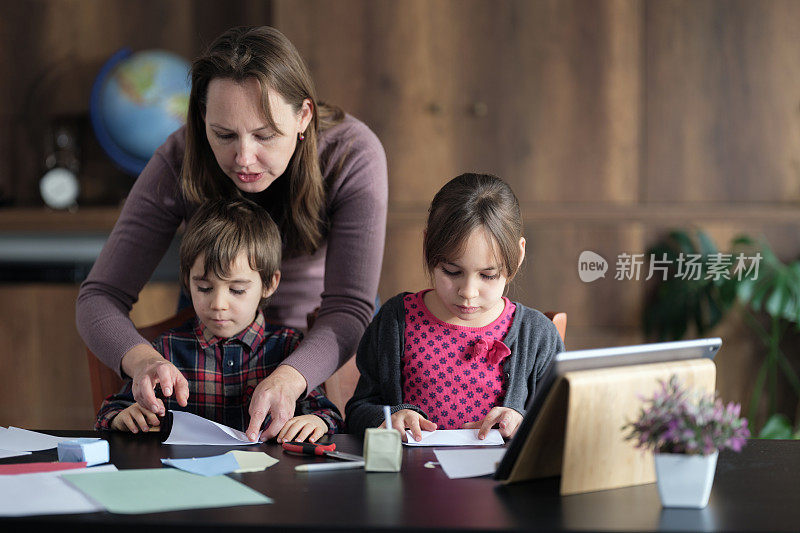 孩子们和妈妈用彩色纸做折纸玩具，按照数码平板电脑视频教程中指示的步骤