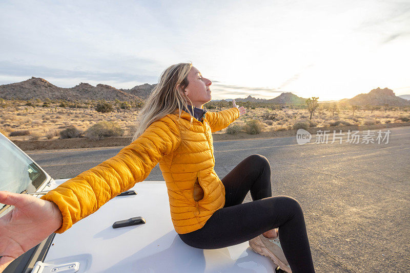 宁静的远景:一个女人从她的汽车引擎盖上凝视着野性的大自然