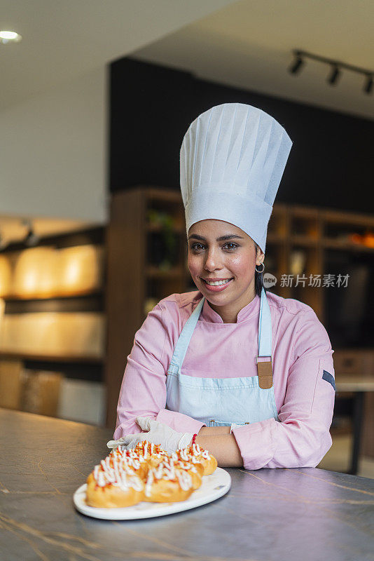 拉丁女职业厨师站在一家漂亮餐厅的厨房里准备美味的菜肴