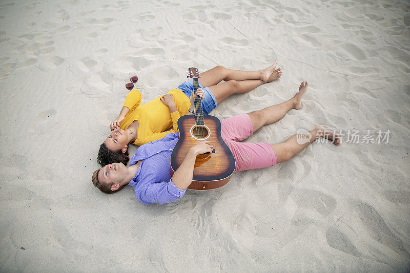 幸福的年轻夫妇躺在沙滩上