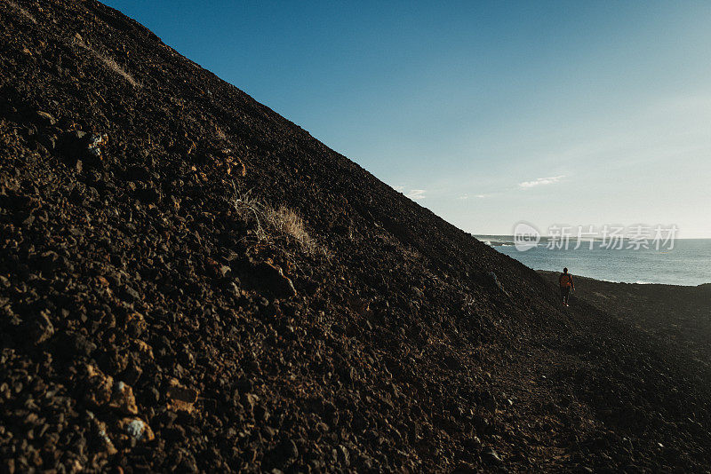 在加那利群岛兰萨罗特岛的火山海岸风景中徒步旅行的妇女