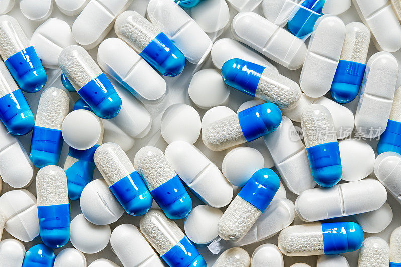 一堆白色、蓝色和其他颜色的药片。塑料包装的药丸。医疗保健和医学的概念