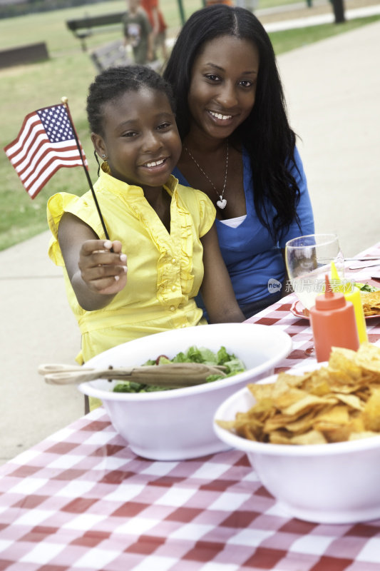 女孩和妈妈在野餐，挥舞美国国旗
