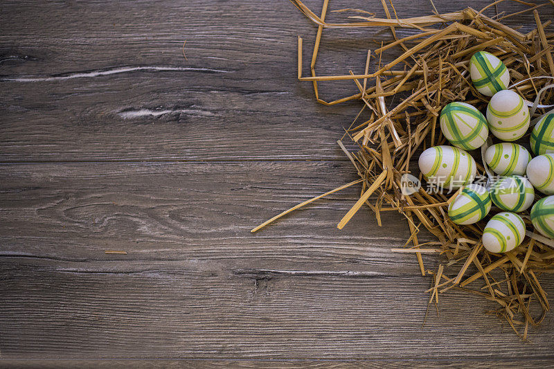 五颜六色的复活节彩蛋放在一张木桌上的稻草窝里