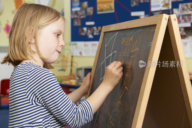 小女孩在学校教室的黑板上写字