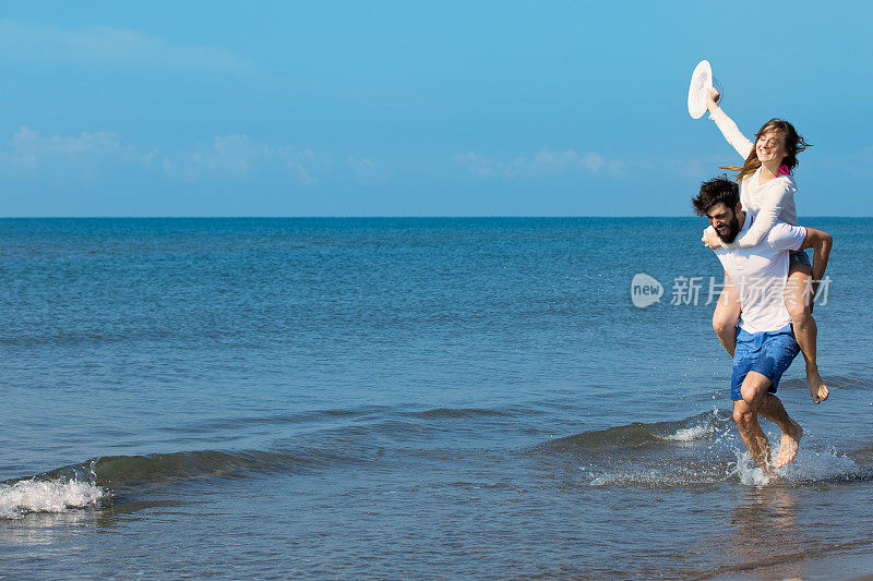 一个背着女孩的男人，在沙滩上，在户外